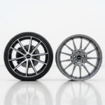 OEM car wheel next to aftermarket rim on white background